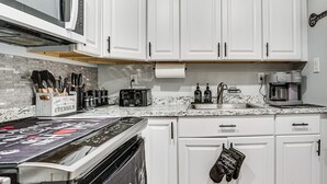 A kitchen with white cabinets, a microwave, a toaster, and a coffee maker.