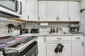 A kitchen with white cabinets, a microwave, a toaster, and a coffee maker. - Work & Play in Baldwin! Cozy Apartment w/ Grill (Baldwin)