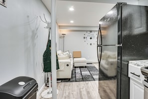 A compact kitchen with a black refrigerator, white cabinets, and a white sofa in the background. - Work & Play in Baldwin! Cozy Apartment w/ Grill (Baldwin)