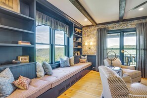 A cozy room with a built-in bench, bookshelves, a round table, and a view of the outdoors.