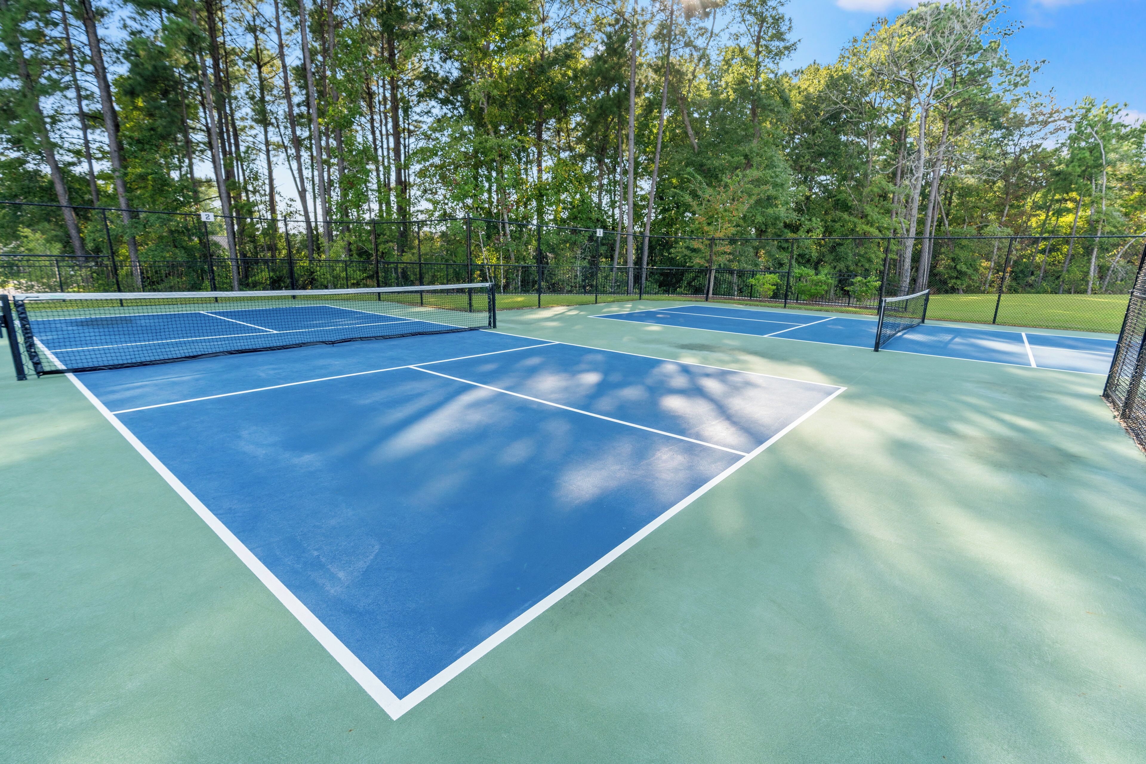 Una cancha de tenis con red, rodeada de árboles.