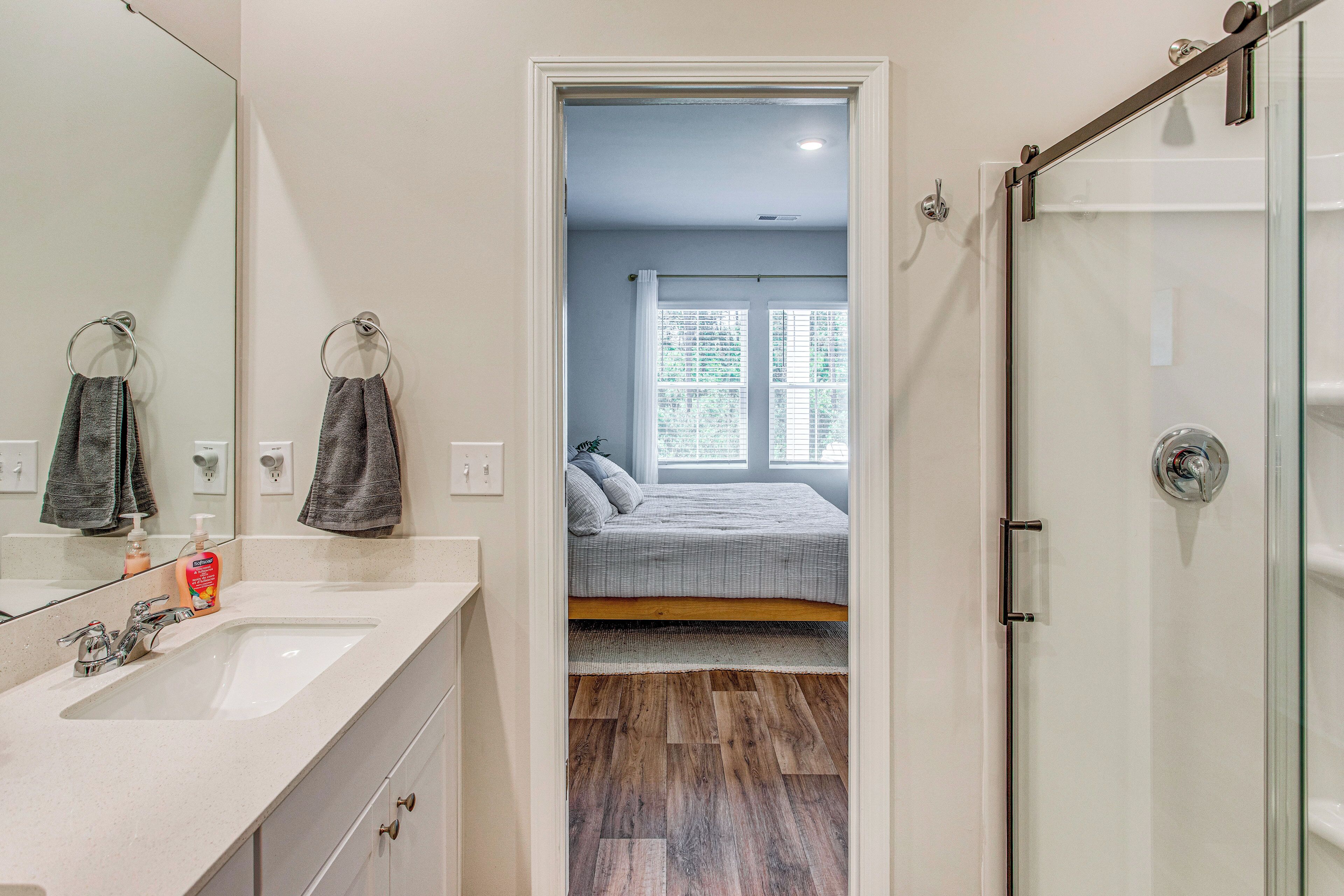 A bathroom with a large mirror, a sink, and a shower.