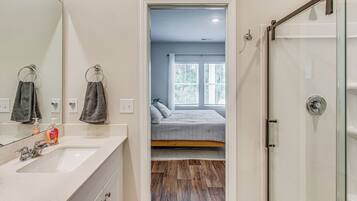 A bathroom with a large mirror, a sink, and a shower.
