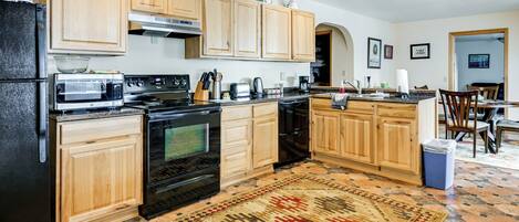 A kitchen with wooden cabinets, a microwave, stove, and a coffee maker.