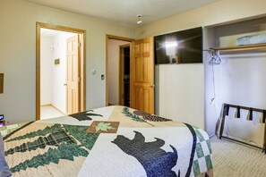 Une chambre à coucher comprenant un lit, une armoire, un miroir et une porte donnant sur une autre pièce.