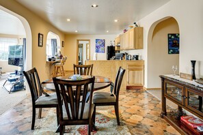 A dining area with a round table and chairs, a kitchen with wooden cabinets, and a tiled floor.