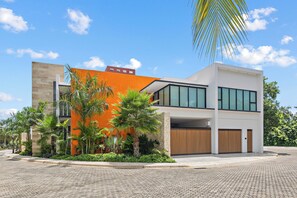 A modern two-story building with a flat roof, large windows, and an orange facade. - Luxury Villa w/ Pier and Beach, Resort Amenities (Cozumel)