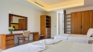 Ein Hotelzimmer mit Schreibtisch, Stuhl, zwei Betten, einem Kleiderschrank und einem Spiegel.