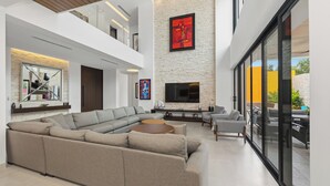 Ein modernes Wohnzimmer mit einem Ecksofa, einem Flachbildfernseher und einem Kamin.
