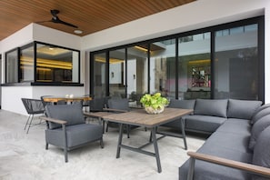 An outdoor patio with a wooden table, grey sofas, and chairs. - Steps to Sea! Luxury Cozumel Villa w/ Resort Perks (Cozumel)