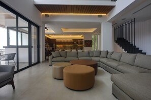 A modern living room with a sectional sofa, ottomans, and a staircase. - Steps to Sea! Luxury Cozumel Villa w/ Resort Perks (Cozumel)