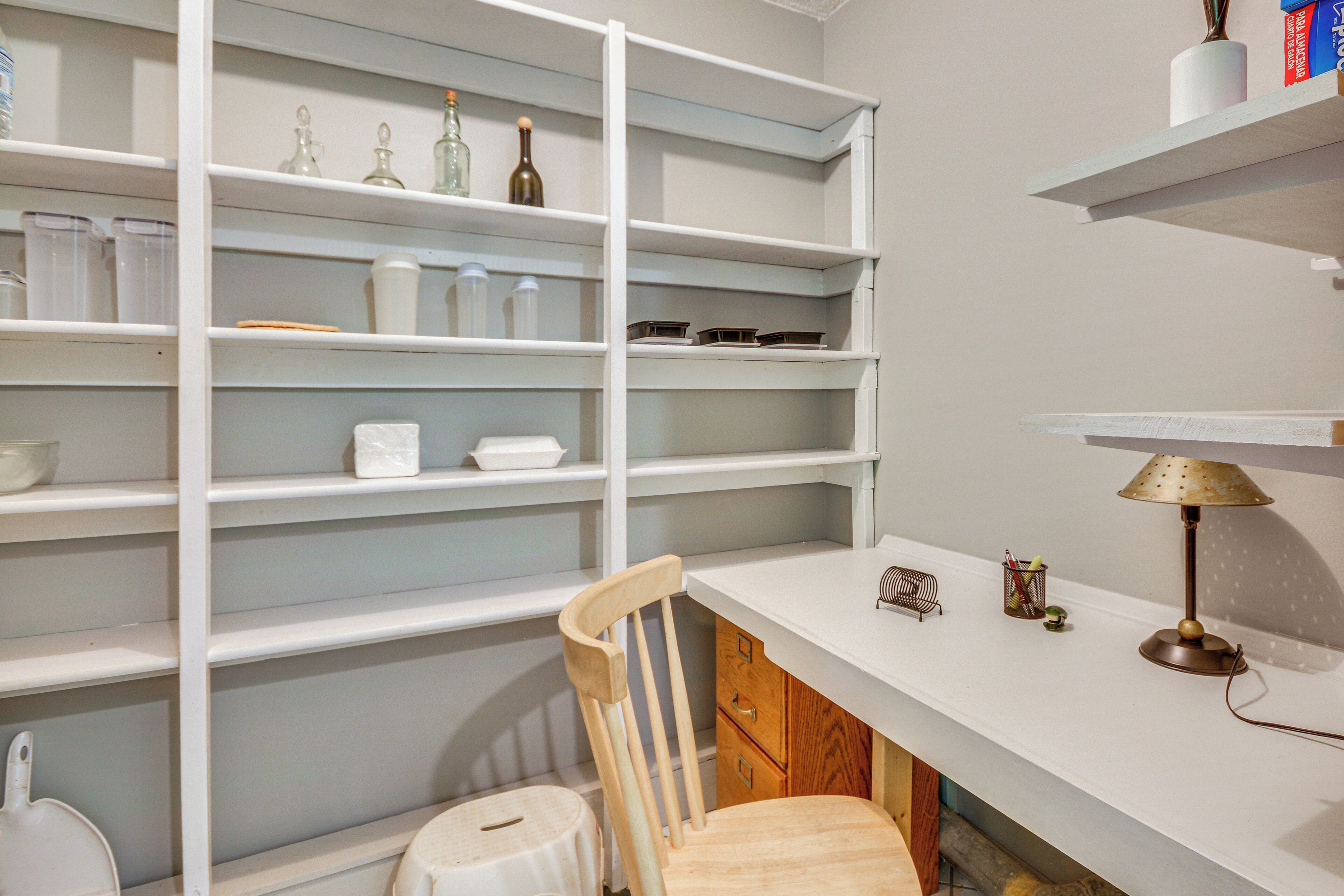 A kitchen with white cabinets, a wooden chair, a white countertop, and a lamp.