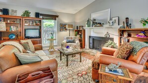 A living room with a fireplace, leather sofas, a television, and a bookshelf. - 1 Mi to Science Center & Park! Pet-friendly Haven (Greensboro)