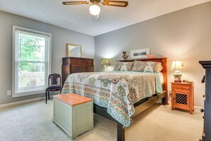Un dormitorio con cama, cómoda, silla y una mesita.