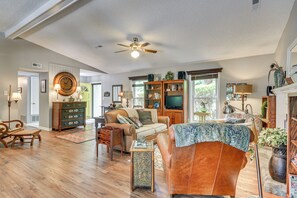 A spacious living room with a ceiling fan, a television, and a fireplace. - 1 Mi to Science Center & Park! Pet-friendly Haven (Greensboro)