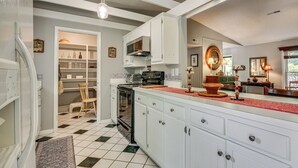 A kitchen with white cabinets, a black stove, and a red rug. - 1 Mi to Science Center & Park! Pet-friendly Haven (Greensboro)