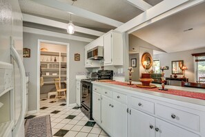 Una cocina con armarios blancos, una estufa negra y un tapete rojo.