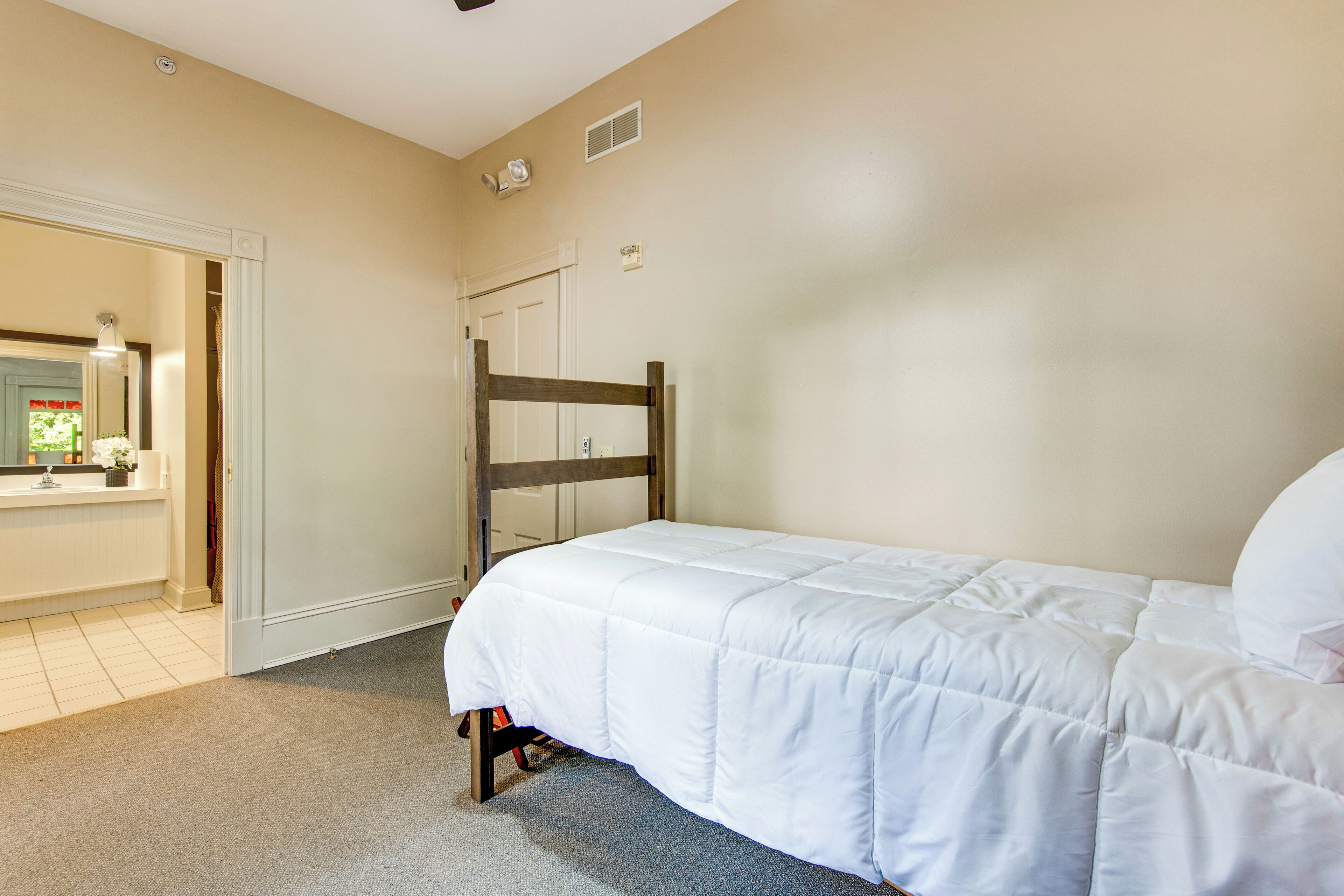 Une chambre à coucher avec un lit, une tête de lit en bois, une porte et un miroir.