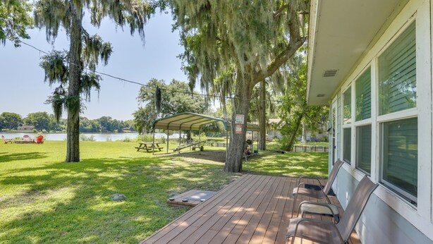 A wooden deck with outdoor seating, a covered picnic table, and a view of a lake.