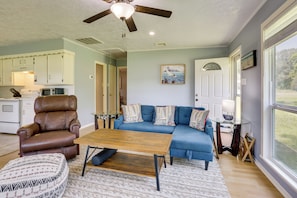 A living room with a brown leather chair, a blue sofa, a wooden coffee table, and a glass side table.