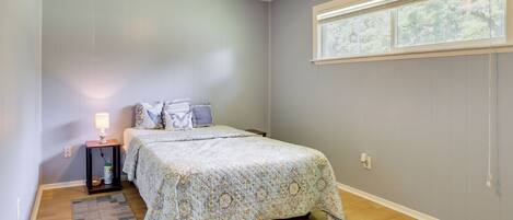 A bedroom with a bed, a nightstand, a lamp, a window, and a ceiling fan.