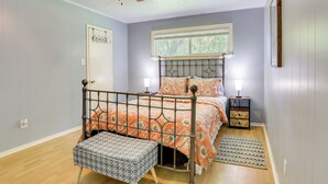 A bedroom with a metal bed frame, a bench, a ceiling fan, a window, and a nightstand.