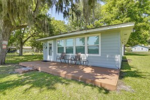 A small, single-story house with a porch, two chairs, and a small table.
