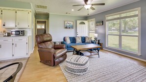A living room with a brown leather chair, a blue sofa, a wooden coffee table, and a large window.