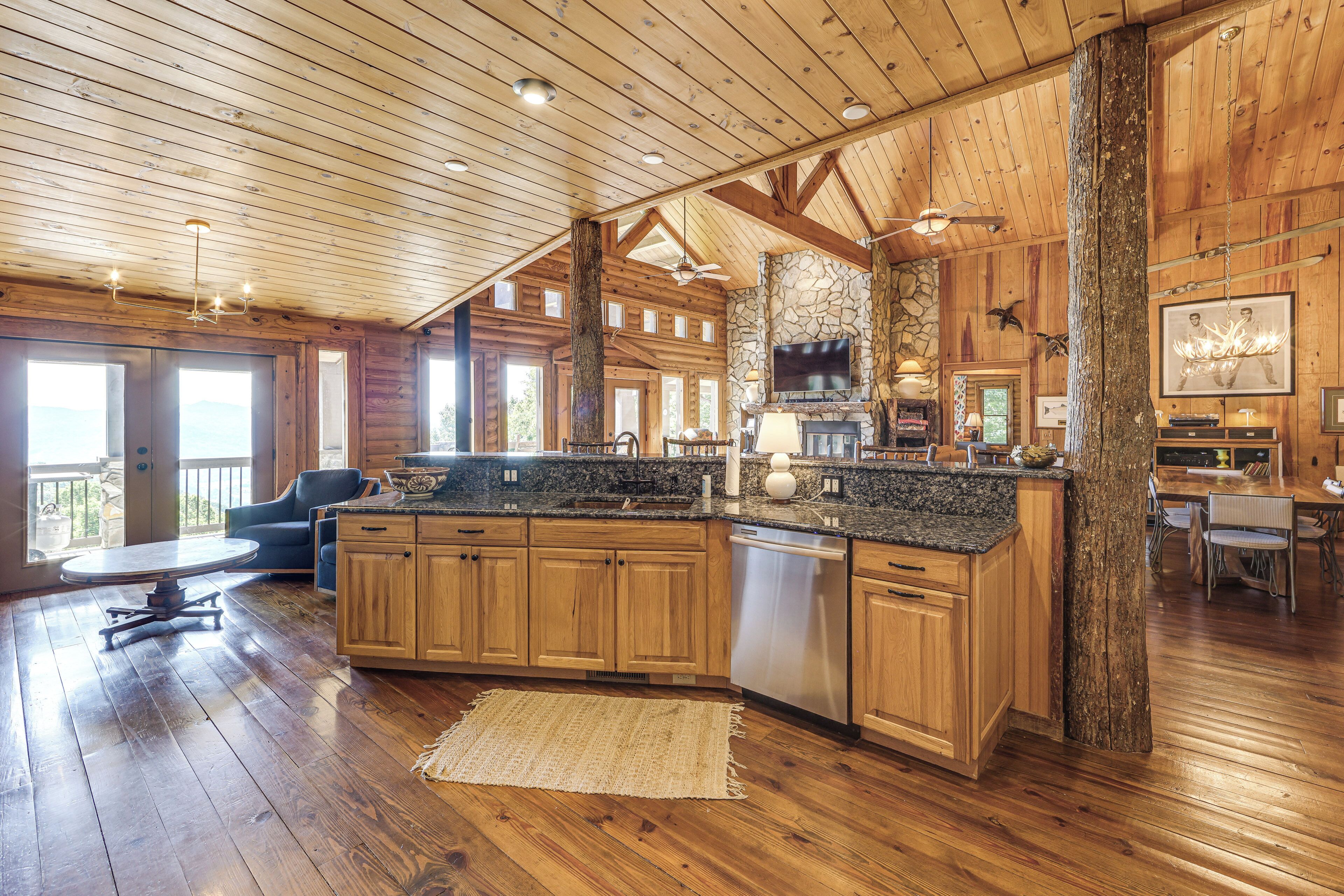 A spacious kitchen with wooden cabinets, a granite countertop, and a stone fireplace.