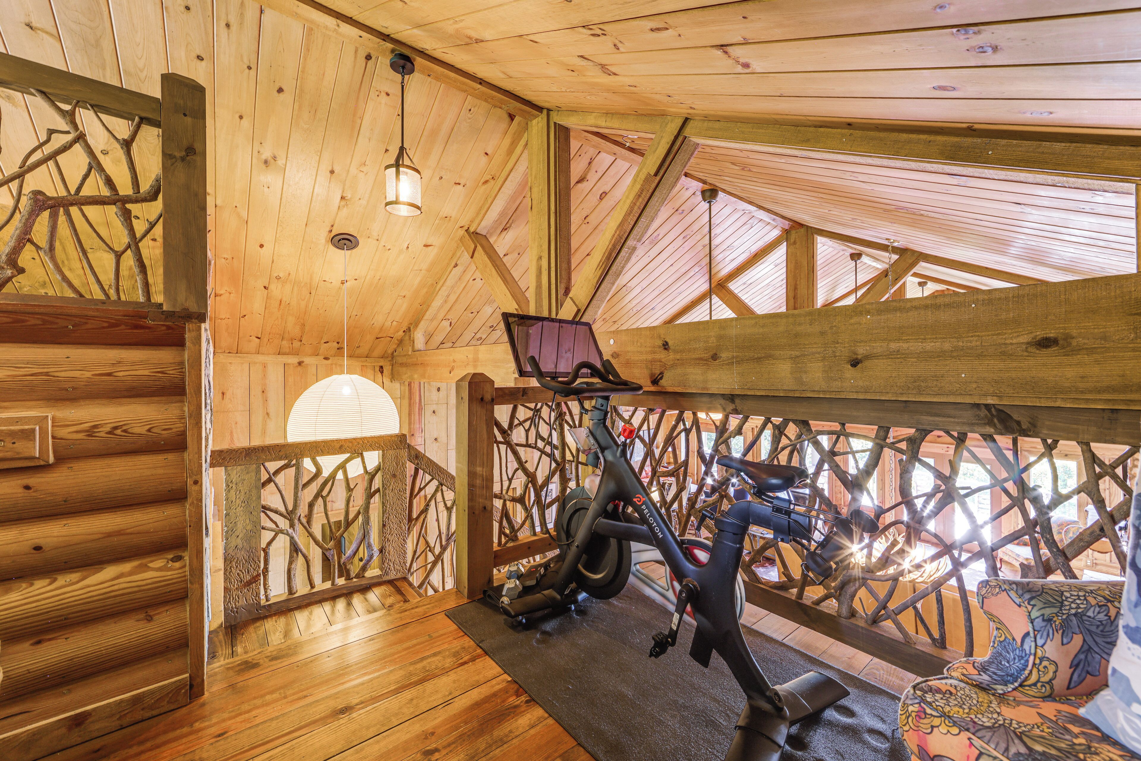 Un intérieur en bois agrémenté d’un vélo, d’un banc rembourré et d’une rambarde en bois.