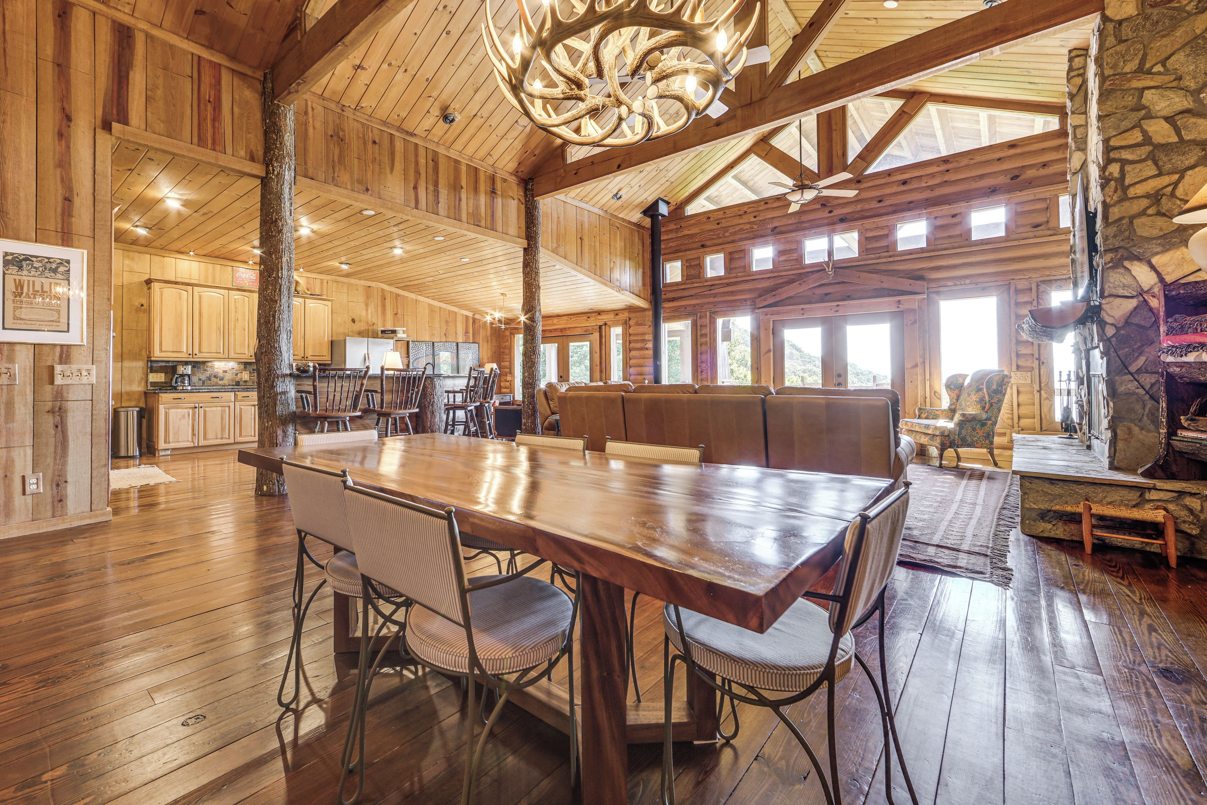 A spacious wooden interior with a large dining table, seating area, and stone accents.
