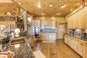 A spacious kitchen with wooden cabinets, granite countertops, and a central island. - Hot Tub + Fire Pit: Spacious Waynesville Escape! (Waynesville)