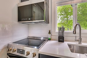 A kitchen with a built-in oven, microwave, and stainless steel sink.