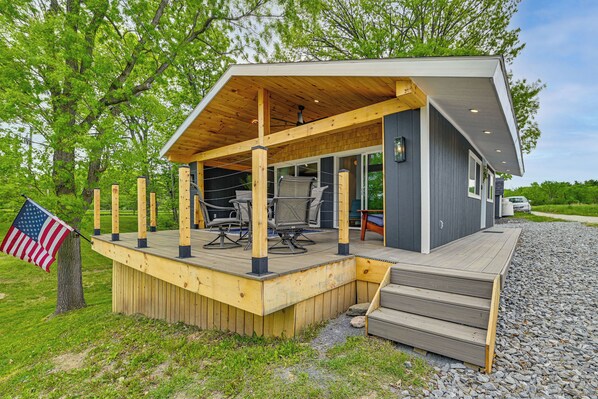 Une maison moderne dotĂ©e dâune terrasse en bois, dâun espace salon extĂ©rieur et dâun drapeau.