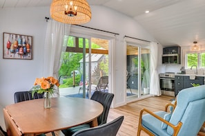 A modern kitchen with a dining area, large windows, and a view of the outdoors.