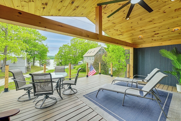 A wooden deck with outdoor furniture, a flag, and a view of a house.