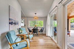 A modern interior with a dining area, wooden flooring, and a large window.