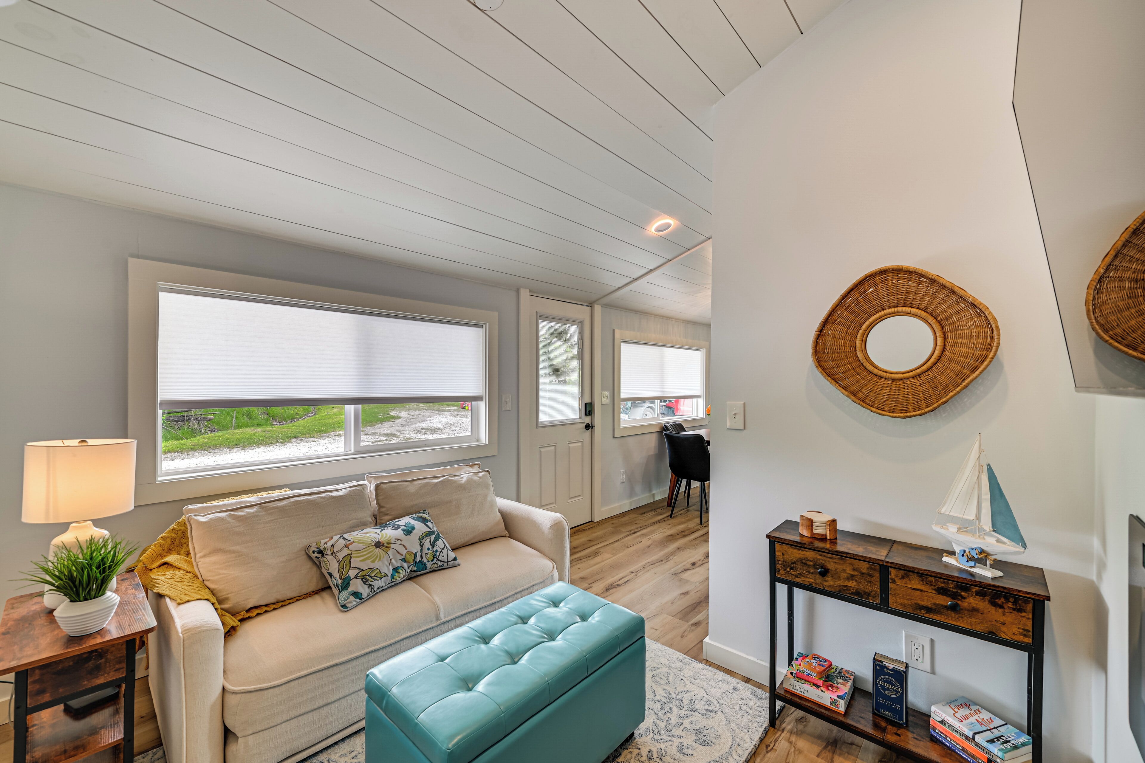 A living room with a sofa, ottoman, and a console table with books and a model ship.