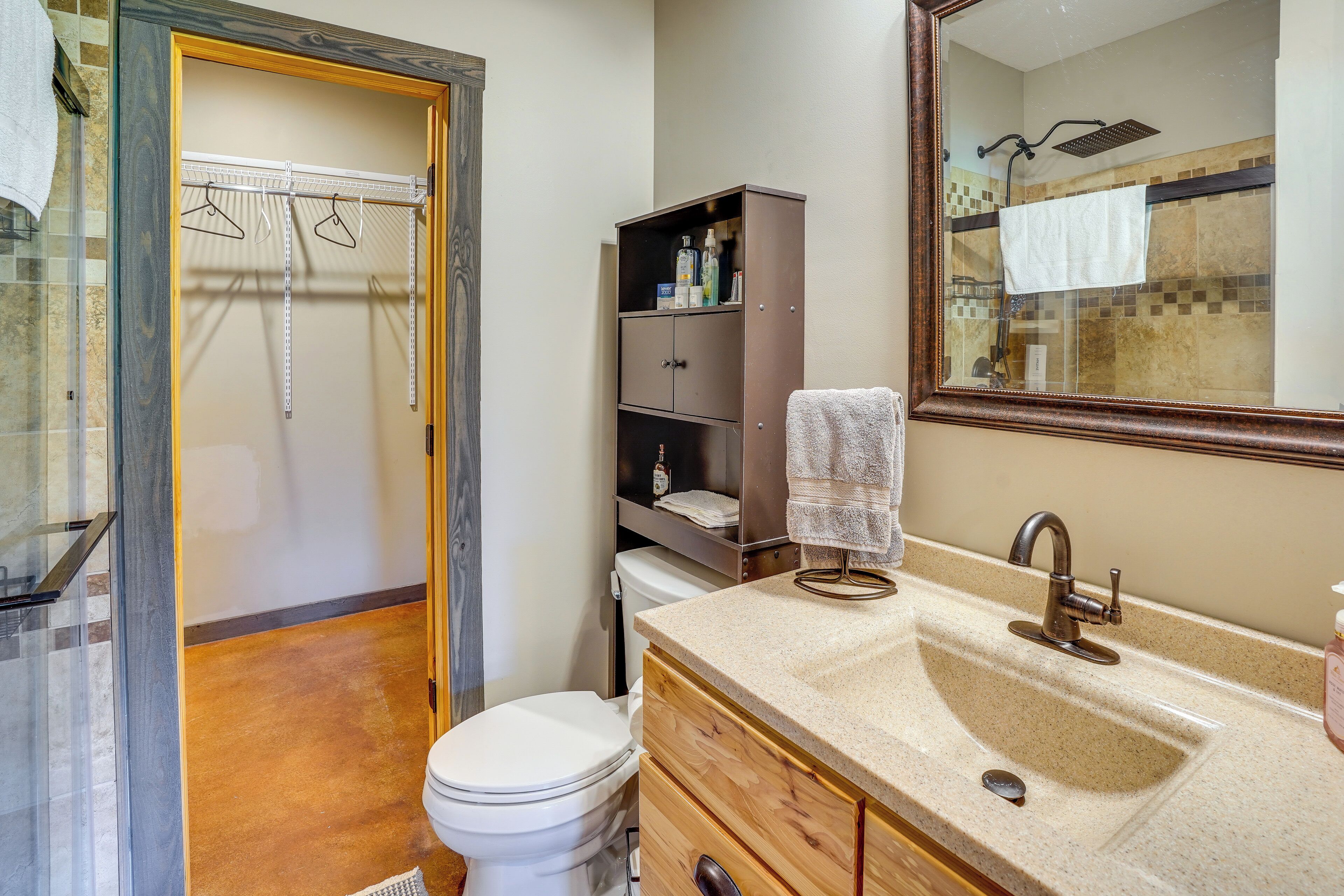 A bathroom with a shower, toilet, vanity with a sink, and a mirror.