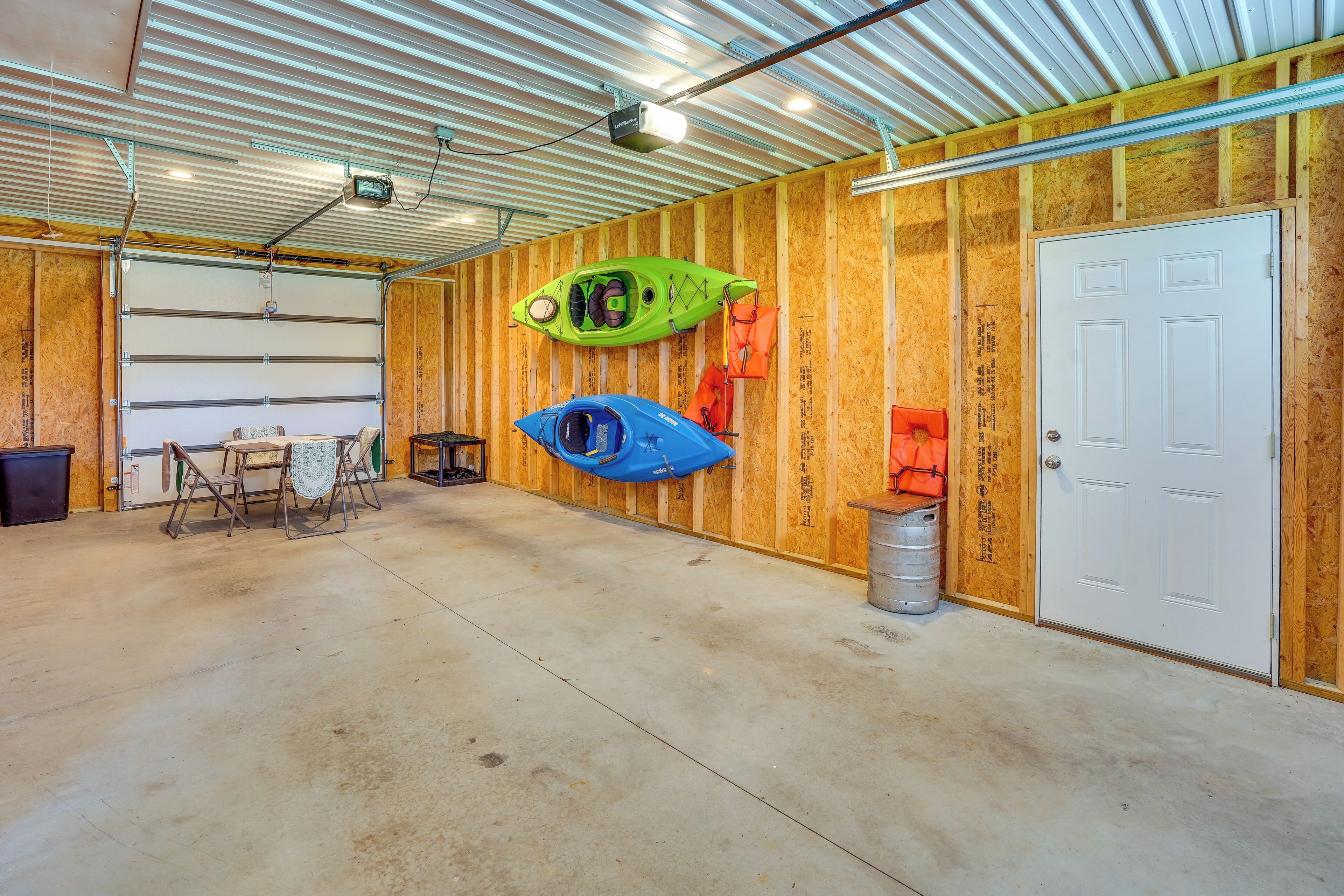 A garage with a concrete floor, wooden walls, a white door, and two kayaks mounted on the wall.