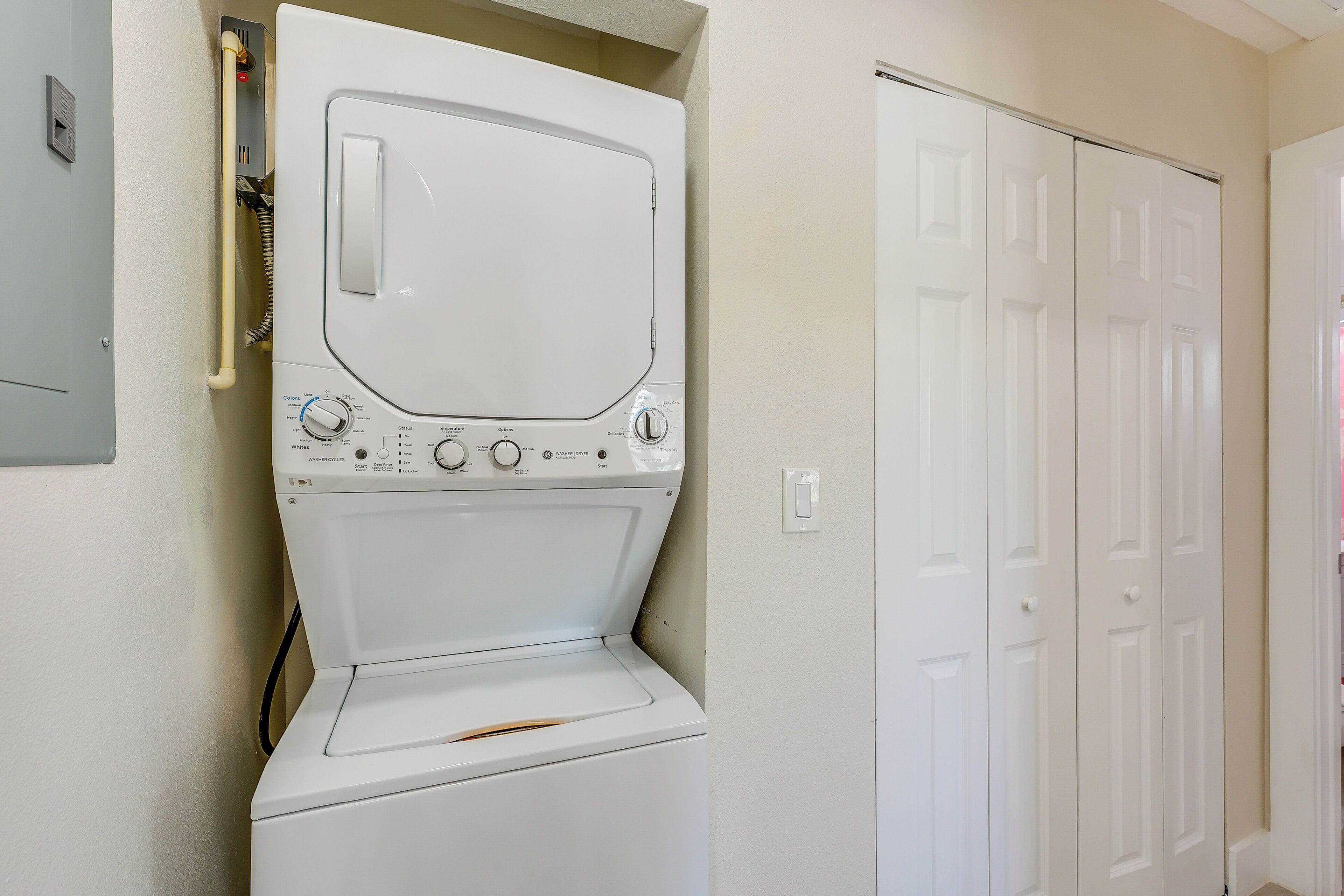 A white washing machine in a laundry room with a white door and a light switch on the wall.
