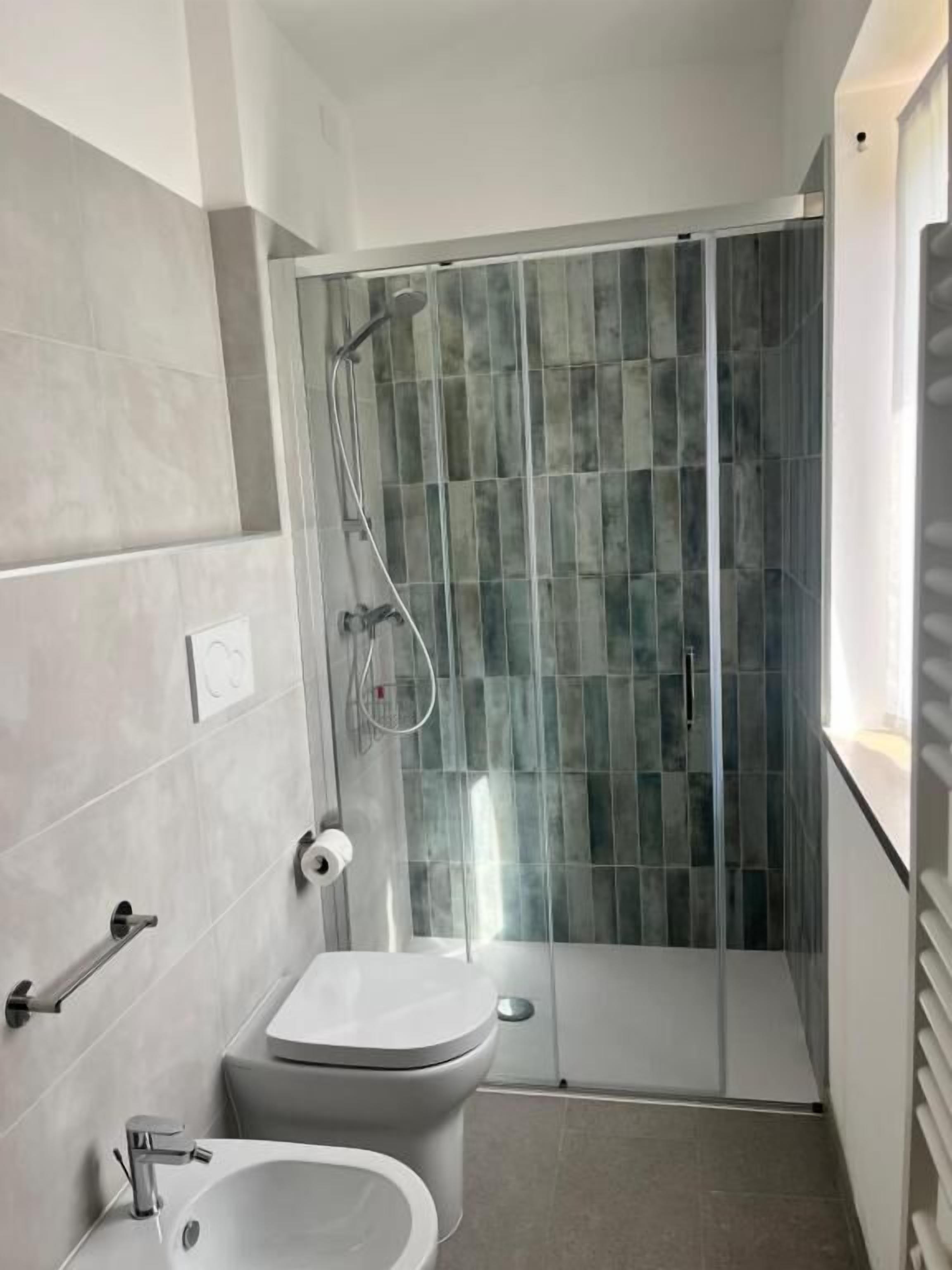 Un baño pequeño con inodoro, bidé y cabina de ducha de vidrio.