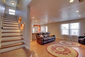 A staircase leading to a second floor, a leather sofa with cushions, and two patterned rugs on a wooden floor. - Extended Stay w/ Hot Tub! 5 Mi to Old Town ABQ (Albuquerque)