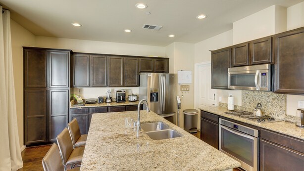 A kitchen with granite countertops, stainless steel appliances, and dark wood cabinets. - Fenced Yard! Family Escape, 1 Mi to Csub (Bakersfield)