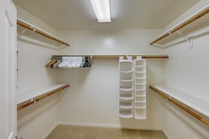 Ein begehbarer Kleiderschrank mit Holzböden, Kleiderstangen und einem Schuhregal.