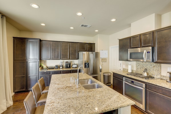 A kitchen with granite countertops, stainless steel appliances, and dark wood cabinets.