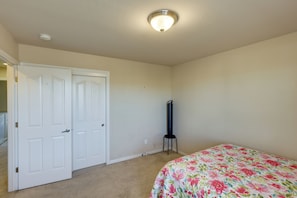 Ein Schlafzimmer mit einem Bett, einer weißen Tür, einer stehenden Lampe und einer Deckenleuchte.