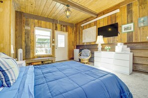 Un dormitorio con una cama grande, paredes de madera, televisión y ventana.