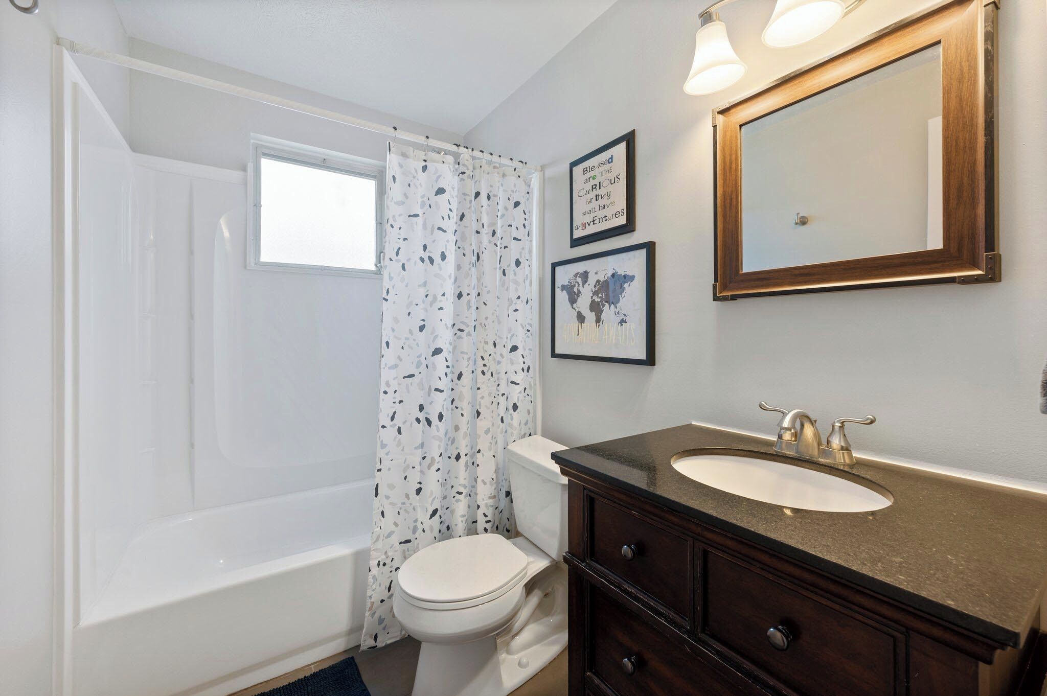 A bathroom with a bathtub, toilet, vanity with a sink, and a mirror.