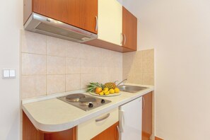 A kitchen with a stove, sink, and wooden cabinets. - Apartment Mondo A2 (Dubrovnik)